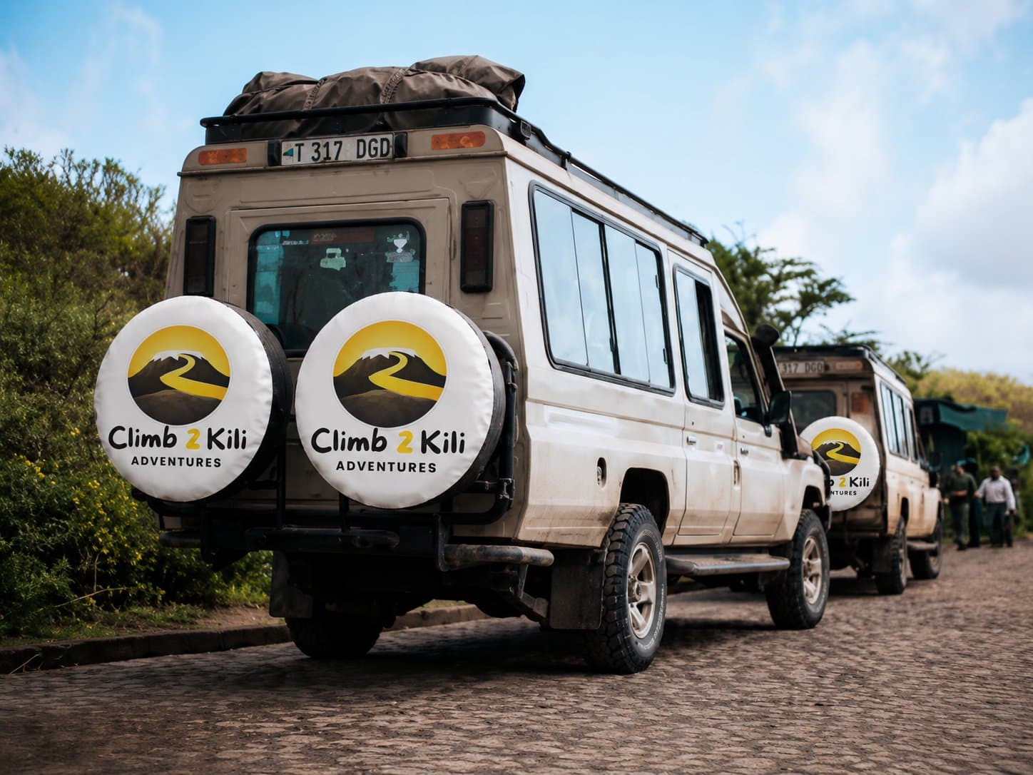 Fundador com guias, carregadores, chefs, motoristas e membros da comunidade local sob o Monte Kilimanjaro
